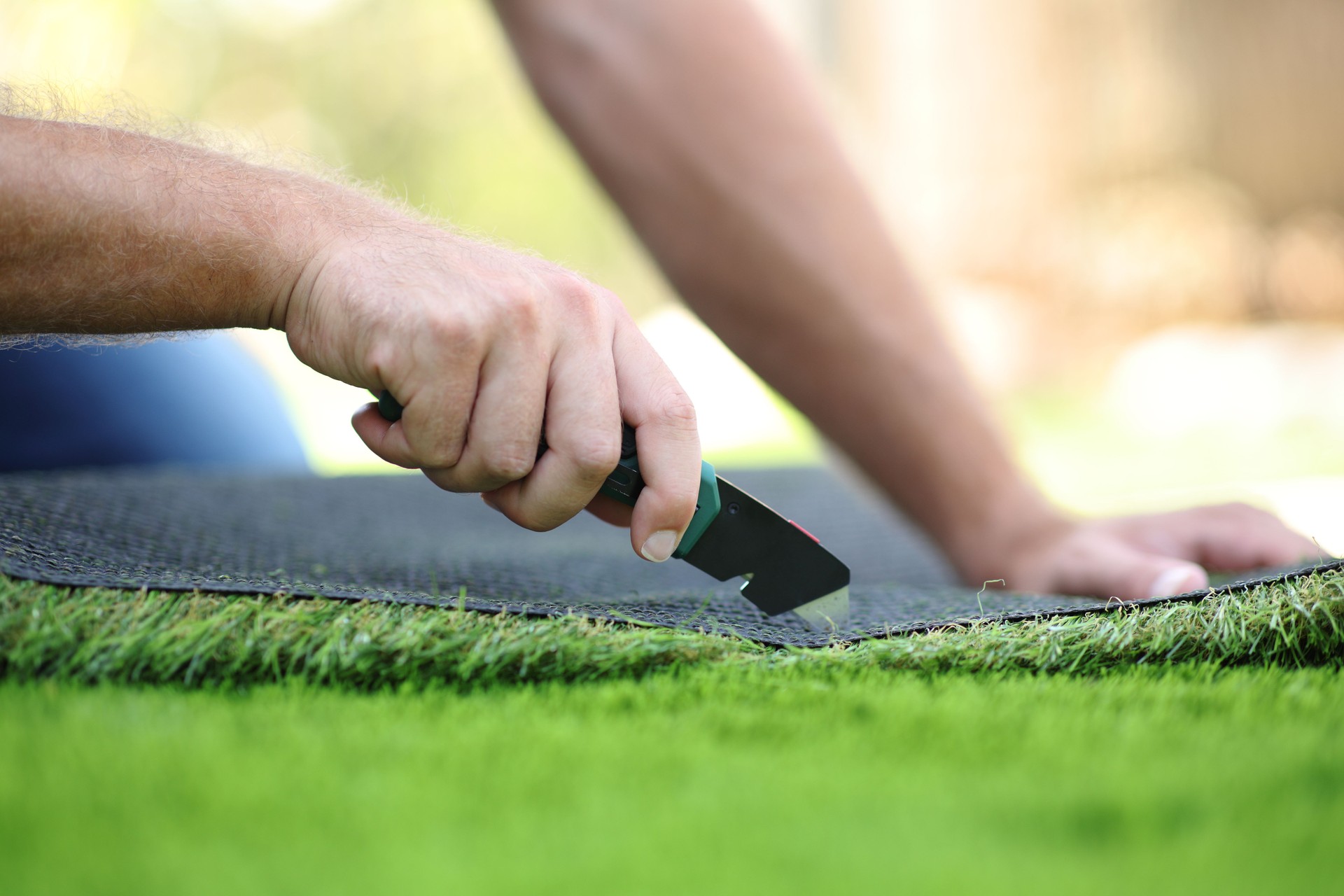Man hand cutting and installing artificial grass